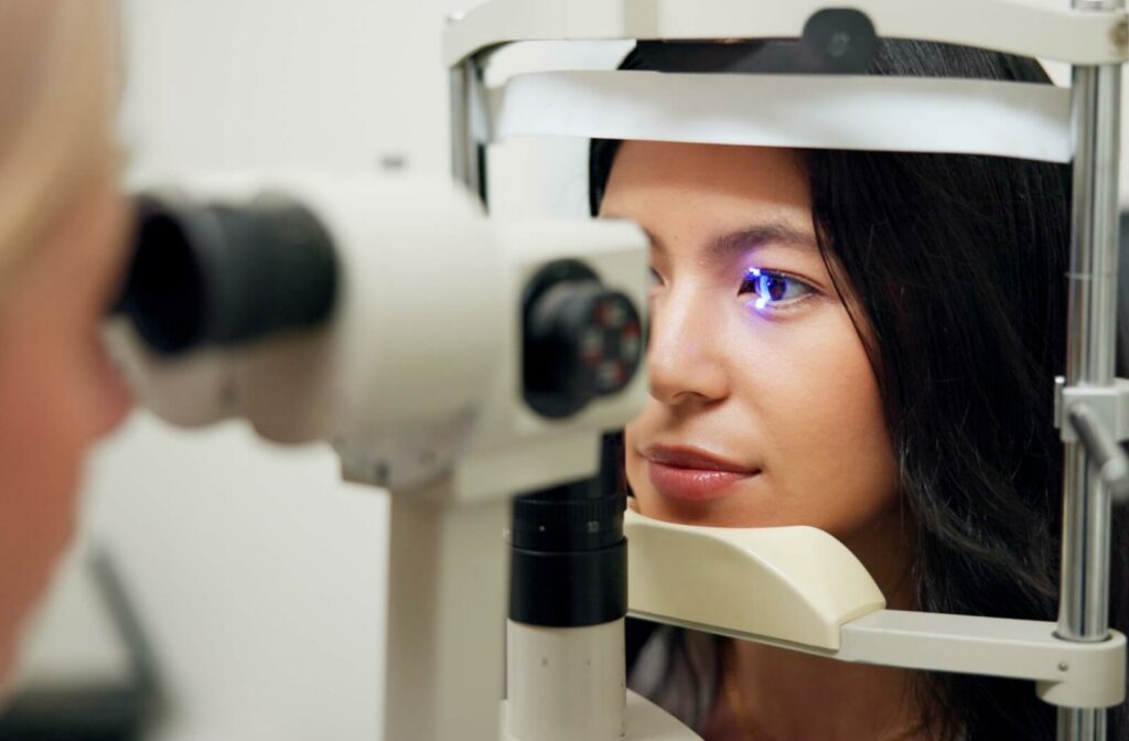 A young adult sits for a slit-lamp eye exam in a well-lit clinic.