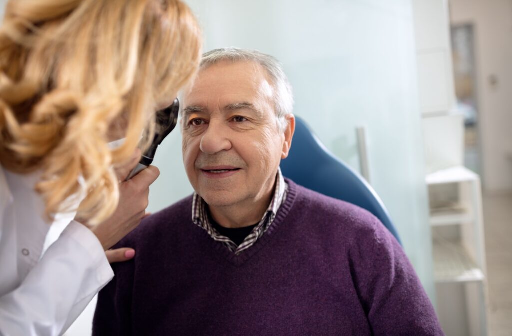 An optometrist examines their older adult patient's eye to determine whether they're a candidate for laser eye surgery to correct presbyopia.