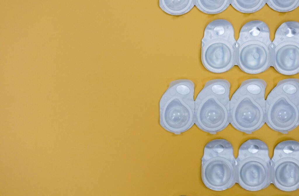 Against a soft yellow background, four rows of disposable contact lenses are arranged on the right side of the image.