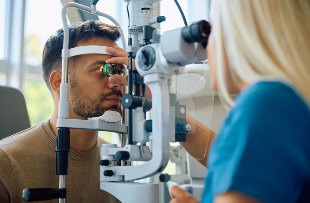 A person sitting down while their eye doctor performs an eye exam.