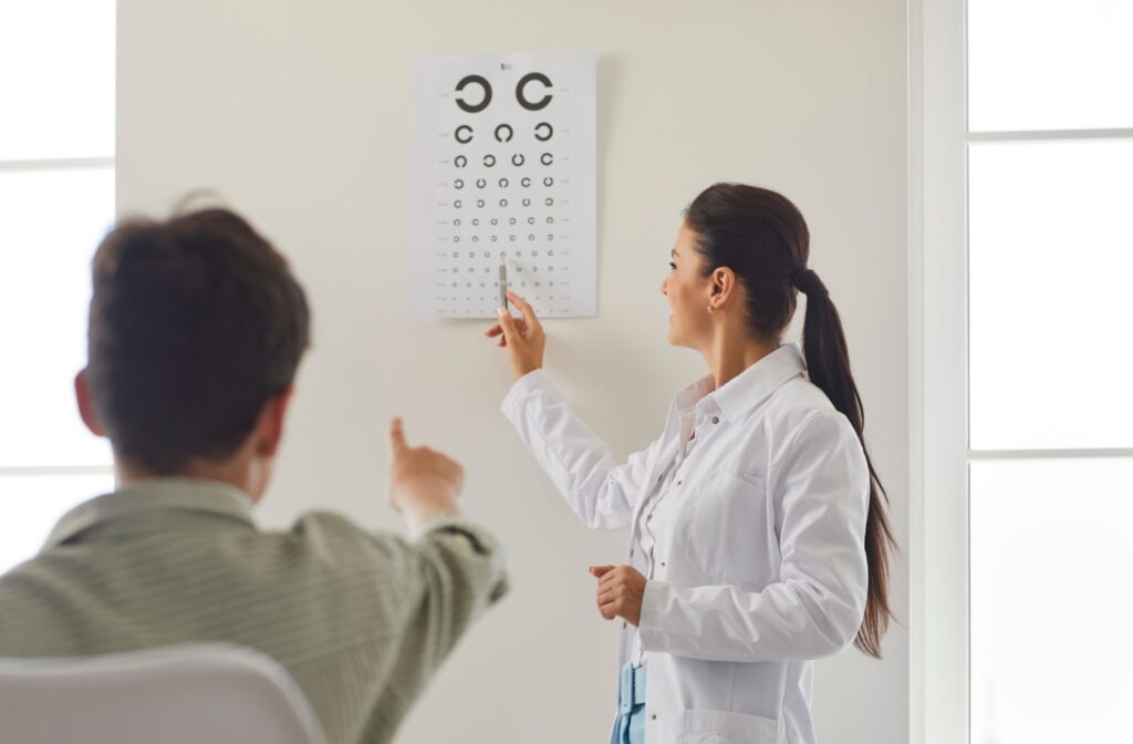 A person reading letters off a chart while their eye doctor points to them.
