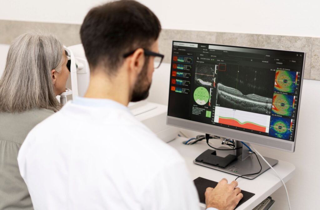 Optometrist reviewing an optical coherence tomography (OCT) scan of a patient’s retina on a computer monitor during an eye exam.